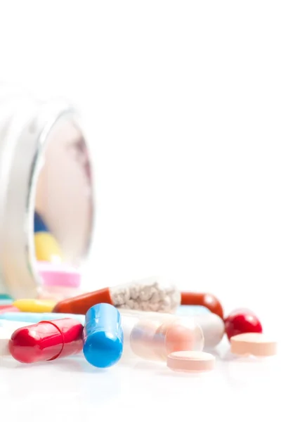 Цветные таблетки в лаборатории перед белым контейнером — стоковое фото