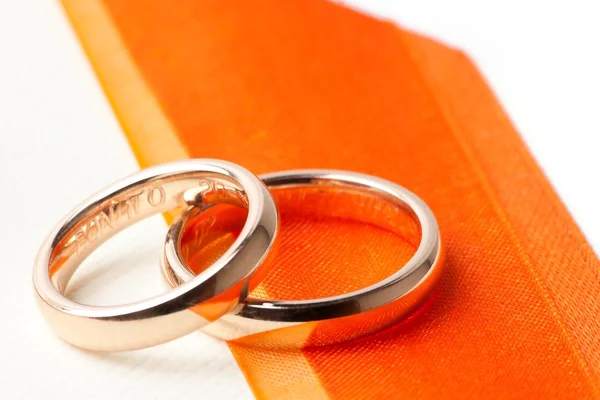 Złote obrączki ślubne w pobliżu pomarańczowe wstążki — Zdjęcie stockowe