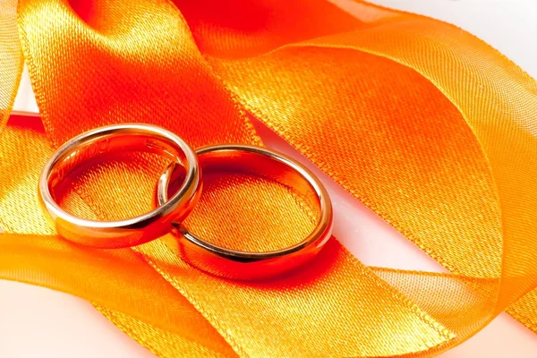 Goldene Trauringe auf orangefarbenem Band — Stockfoto