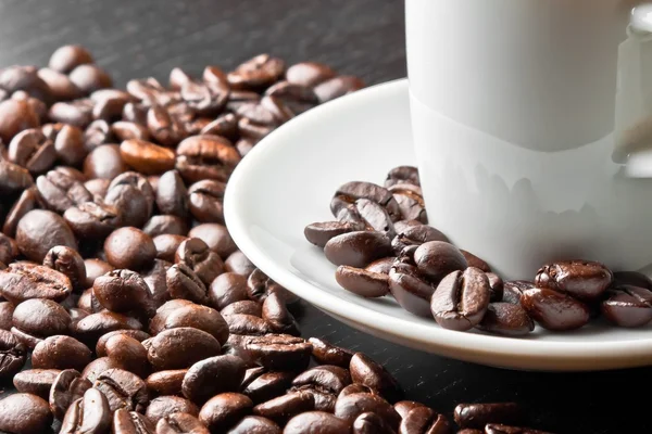 White cup with coffee near coffee beans — Stock Photo, Image