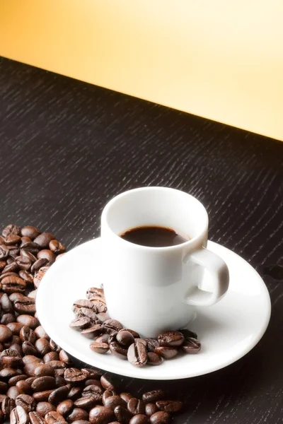 White cup with coffee near coffee beans — Stock Photo, Image