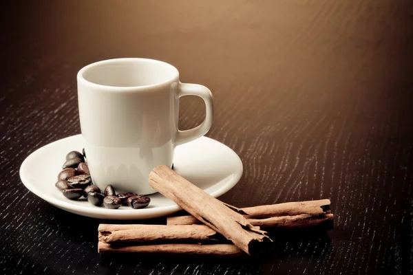 Taza blanca con café cerca de granos de café sobre mesa de madera — Foto de Stock