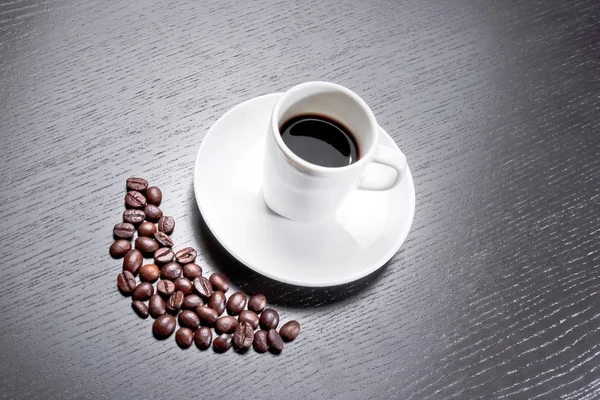 White cup with coffee near coffee beans — Stock Photo, Image