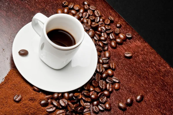 White cup with coffee near coffee beans — Stock Photo, Image