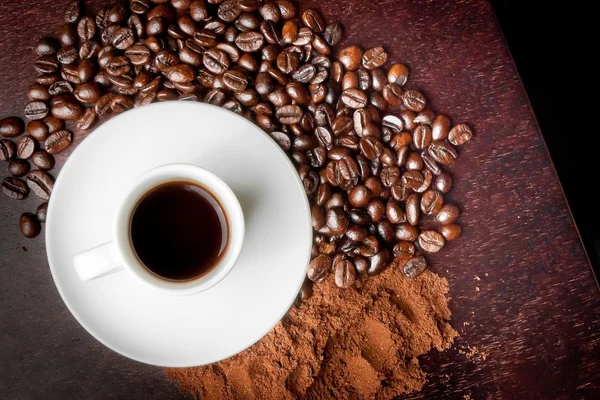 Taza blanca con café cerca de granos de café y polvo de café —  Fotos de Stock