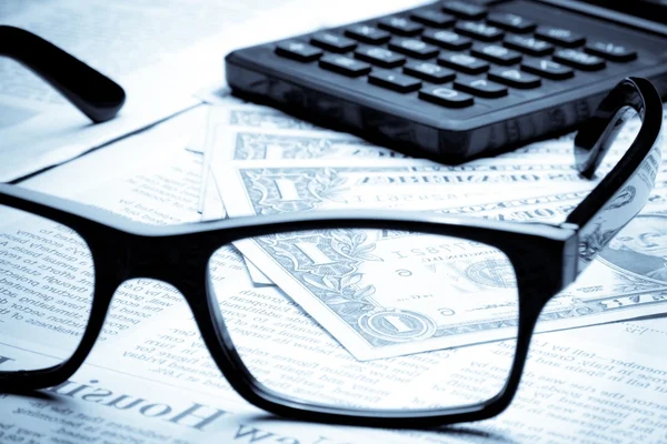 Detail of dollars on business newspaper near calculator — Stock Photo, Image
