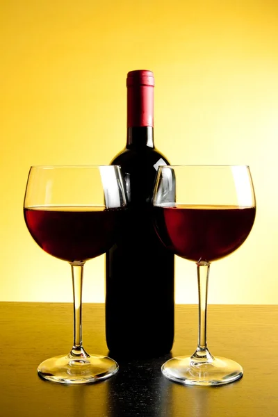 Two red wine glasses near bottle — Stock Photo, Image