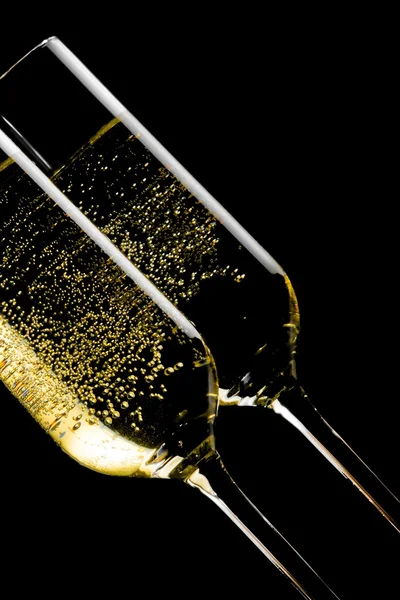 Detail van een paar gekanteld fluiten van champagne met gouden bubbels — Stockfoto