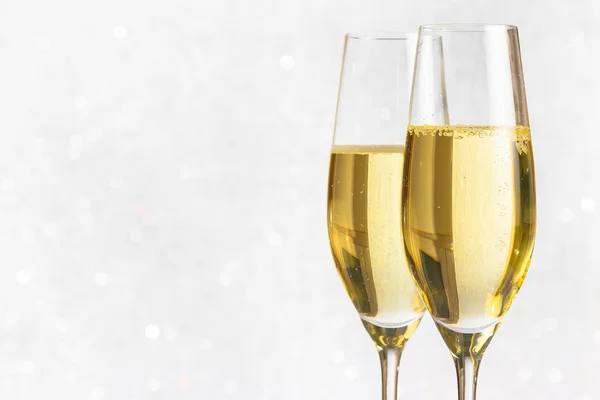 A pair of flutes of golden champagne on silver bokeh — Stock Photo, Image