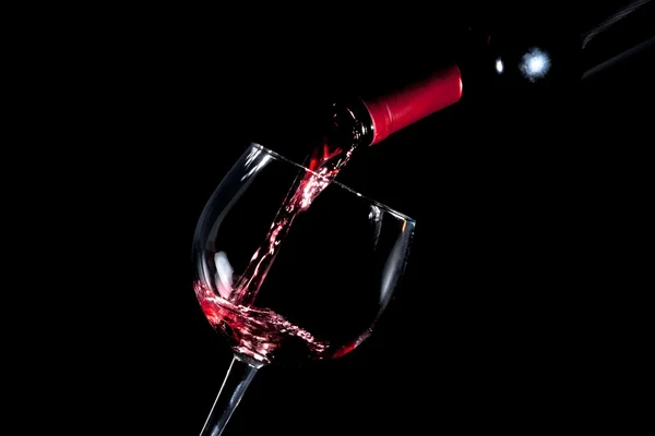 Pouring red wine glass black background — Stock Photo, Image