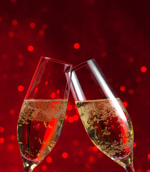 Two champagne flutes on red light bokeh background — Stock Photo, Image