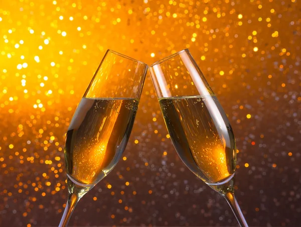 Par en champagne flöjter på gyllene ljus bokeh bakgrund — Stockfoto