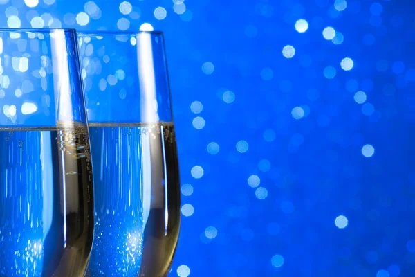 Par en champagne flöjter på blå ljus bokeh bakgrund — Stockfoto