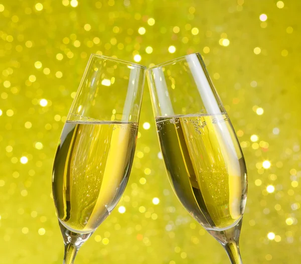 Duas flautas de champanhe com bolhas douradas no fundo bokeh luz amarela — Fotografia de Stock