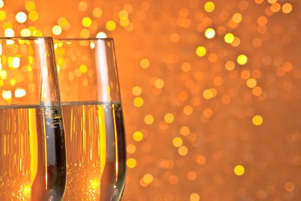 Pair of a champagne flutes on orange and yellow light bokeh background — Stock Photo, Image