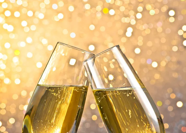 Detail of a champagne flutes with golden bubbles on light bokeh background — Stock Photo, Image