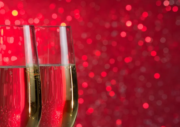 Pair of a champagne flutes on red light bokeh background — Stock Photo, Image