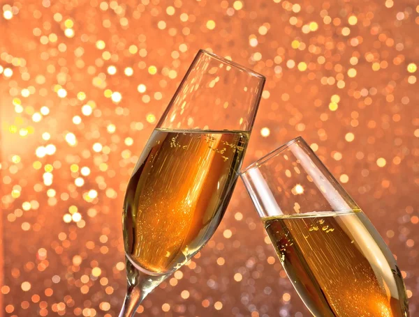 Pair of a champagne flutes with gold bubbles on light bokeh background — Stock Photo, Image