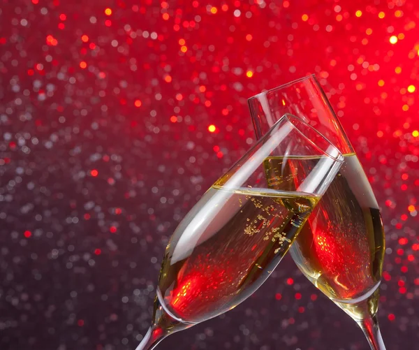 Champagner-Flöten mit Goldblasen auf rotem und violettem Licht Bokeh Hintergrund — Stockfoto