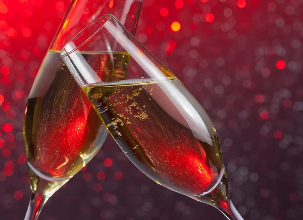 Champagner-Flöten mit Goldblasen auf Rotlicht-Bokeh-Hintergrund — Stockfoto