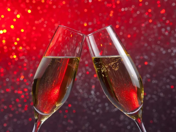 Pair of a champagne flutes with gold bubbles on red and violet light bokeh background — Stock Photo, Image