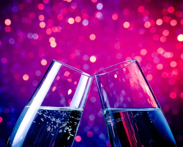Šampaňské flétny zlaté bubliny na modrý odstín světle bokeh pozadí — Stock fotografie