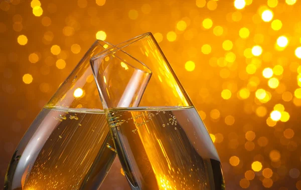 Two champagne flutes with gold bubbles on dark light bokeh background — Stock Photo, Image