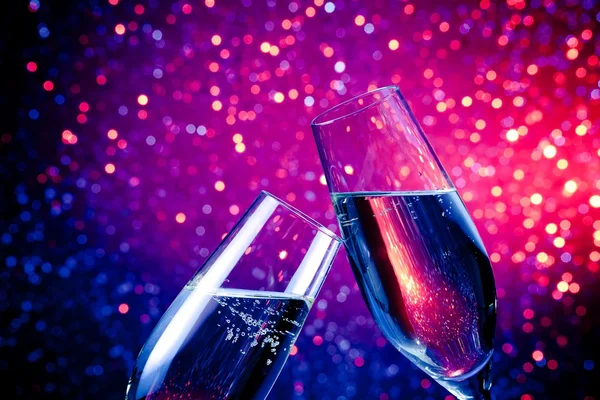 Champagne flutes with gold bubbles on blue tint light bokeh background — Stock Photo, Image