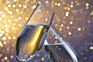 champagne flutes with golden bubbles on light bokeh background