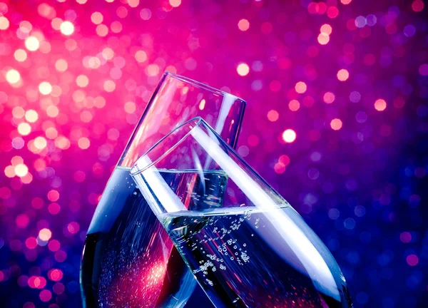 Шампанского флейты с золотыми пузырьками на голубом и фиолетовом оттенках света bokeh фон — стоковое фото