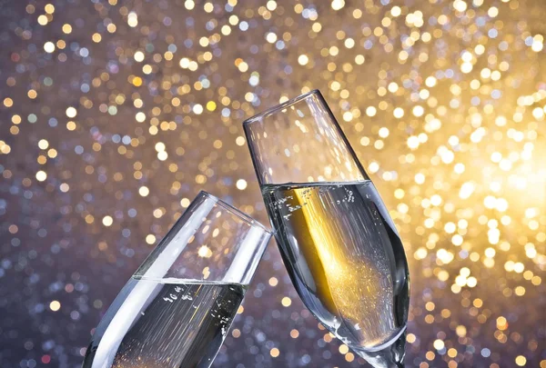 Champagne flutes with golden bubbles on light bokeh background — Stock Photo, Image