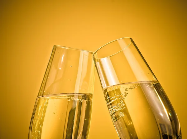 Una coppia di flauti champagne con bollicine dorate su fondo chiaro dorato — Foto Stock