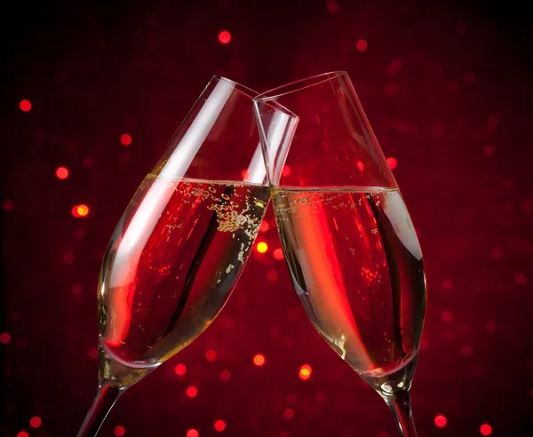 A pair of champagne flutes on red dark light bokeh background — Stock Photo, Image