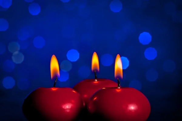 Červené vánoční svíčky na pozadí modré bokeh — Stock fotografie