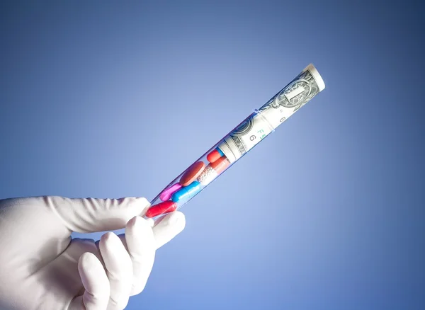 Pastile colorate și dolari în tub de testare într-o mână, costul asistenței medicale — Fotografie, imagine de stoc