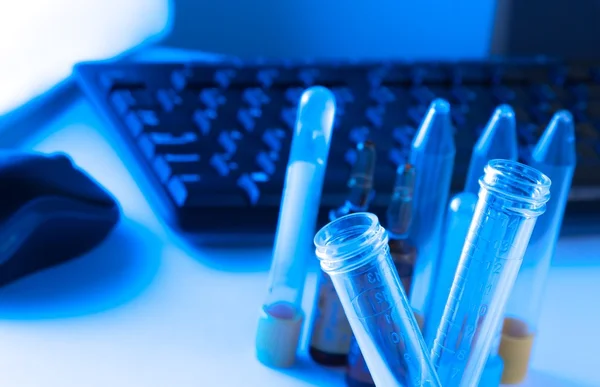 Test tubes in laboratory on table near computer keyboard and mouse — Stock Photo, Image