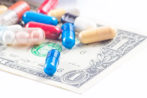 Pílulas coloridas em dólar americano, custo de cuidados médicos — Fotografia de Stock