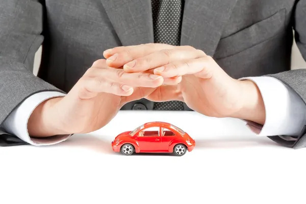 Homme d'affaires protéger avec ses mains une voiture rouge, concept d'assurance, achat, location, carburant ou frais de service et de réparation — Photo