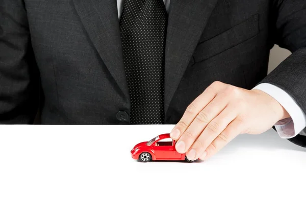 Carro de brinquedo e mão de homem de negócios, conceito de seguro, compra, aluguel, combustível ou serviço e custos de reparação — Fotografia de Stock