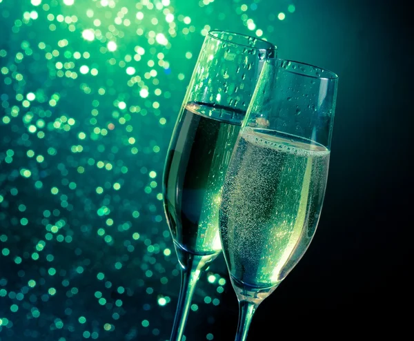 Flautas de champanhe com bolhas douradas no fundo bokeh luz verde escuro — Fotografia de Stock