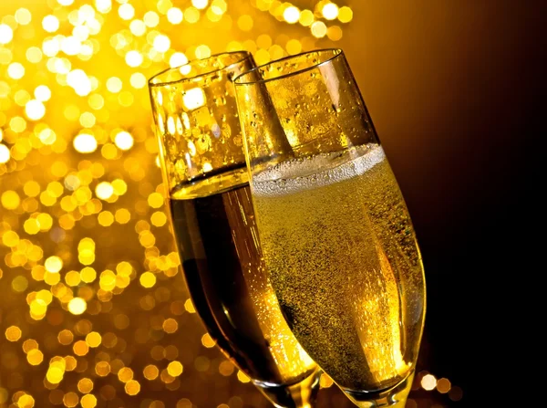 Detalhe de flautas de champanhe com bolhas douradas no fundo bokeh luz dourada escuro — Fotografia de Stock