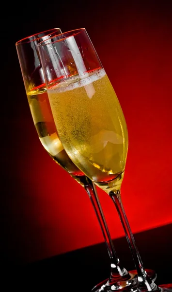 Flautas de champán con burbujas doradas sobre fondo claro rojo oscuro —  Fotos de Stock