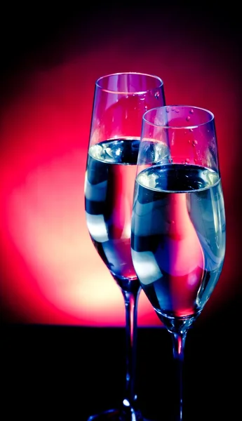 Flautas de champanhe com bolhas douradas no fundo de luz azul escuro e violeta — Fotografia de Stock