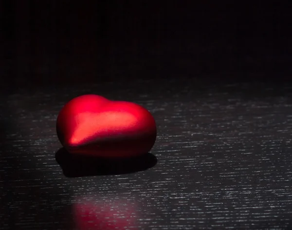 Rotes Herz isoliert auf schwarzem Holztisch, Konzept des Valentinstages — Stockfoto