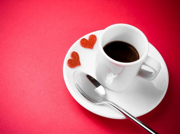 Decorative red hearts near cup of coffee on red table, concept valentine day — Stock Photo, Image