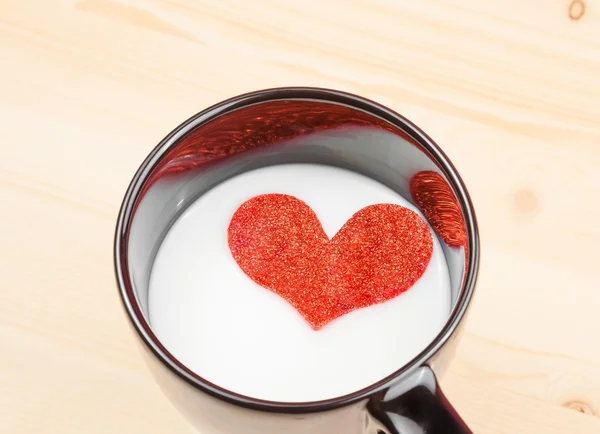 Milchbecher mit dekorativem Herzen auf Holztisch, Konzept des Valentinstages — Stockfoto