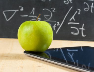Dijital tablet pc ve yeşil elma yazı tahtası ahşap masa üzerinde önünde