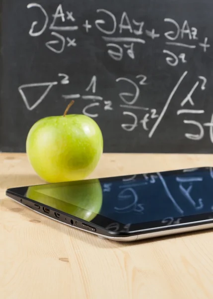 Tablet pc 和绿色苹果木桌上的黑板前 — 图库照片