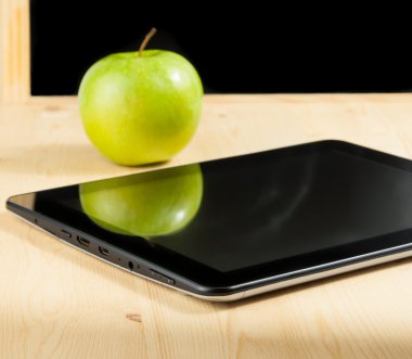 Dijital tablet pc ve yeşil elma yazı tahtası ahşap masa üzerinde önünde