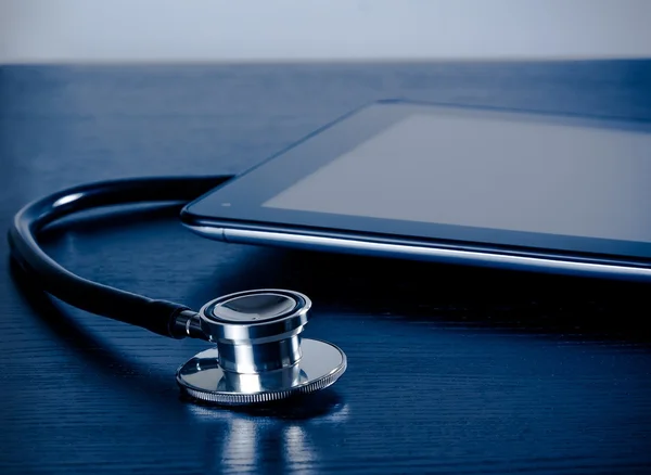 Medical stethoscope near modern digital tablet pc in laboratory on wood table — Stock Photo, Image